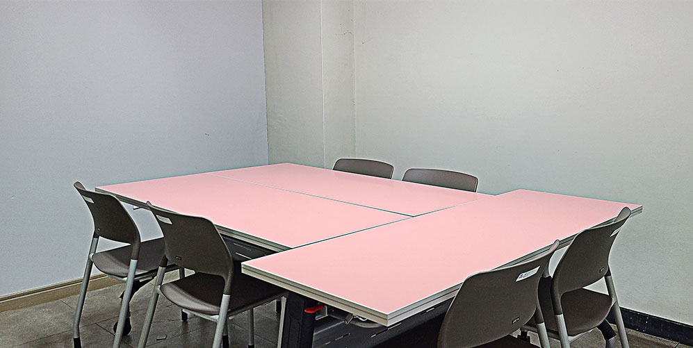 긴 직사각형의 분홍색테이블3개와 의자6개가 배치되어 있는 모습